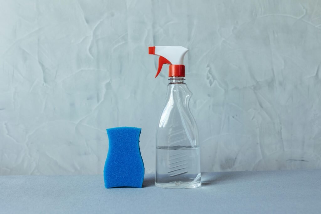 pexels-photo-28576626-28576626 A spray bottle and blue sponge on a textured grey surface. Perfect for cleaning themes.